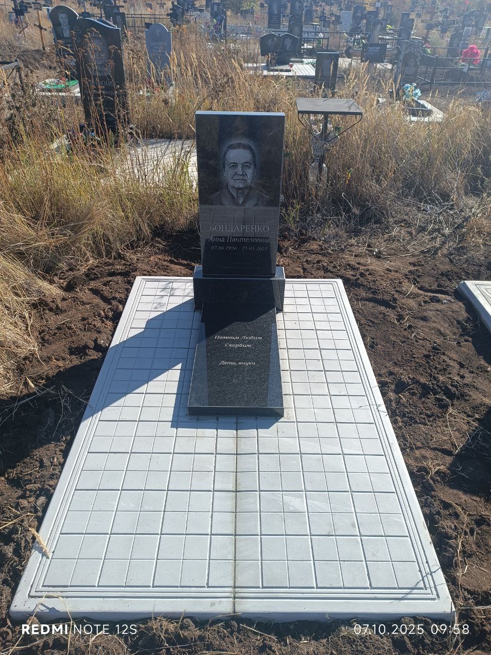 Гранитный памятник с надгробной плитой на площадке